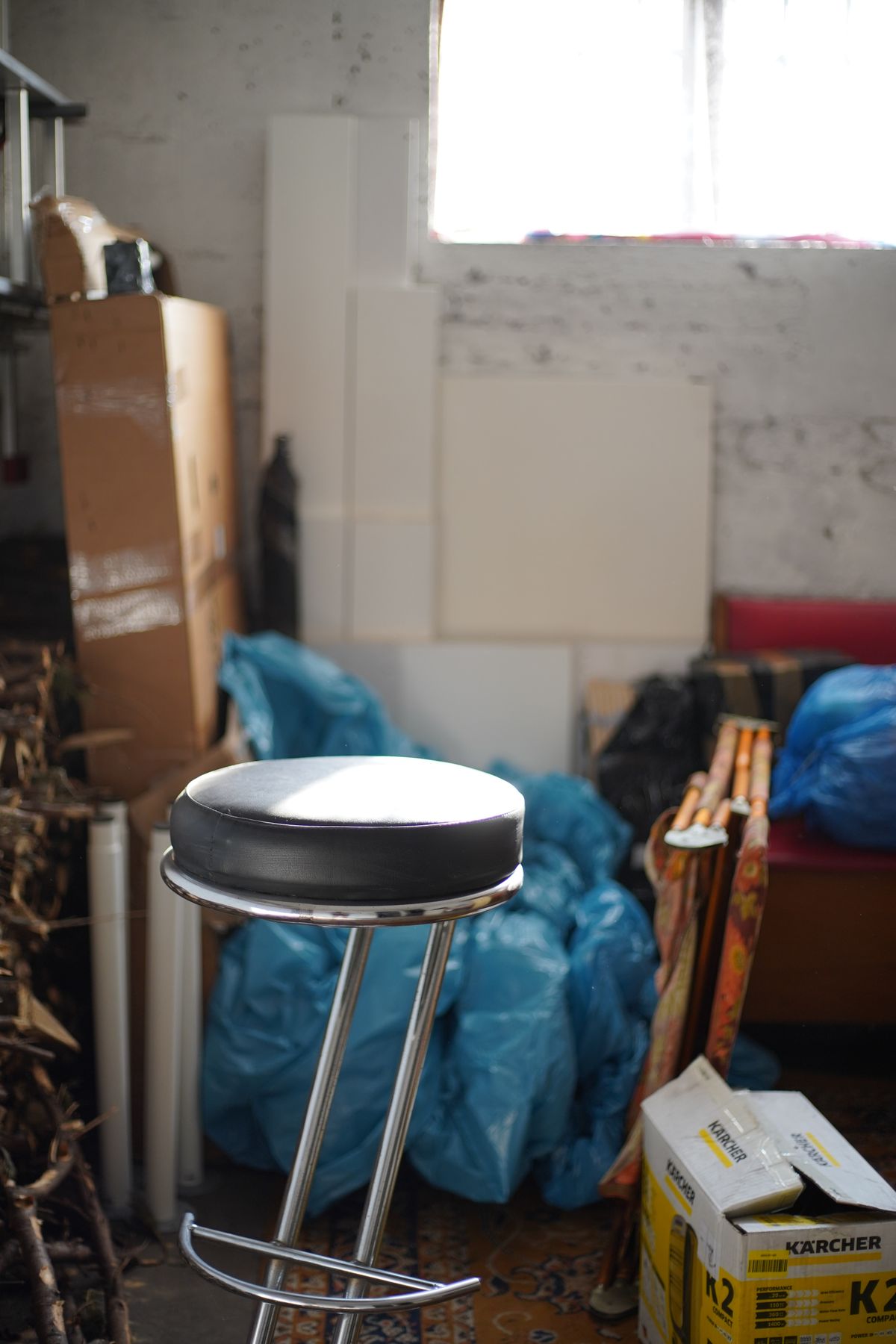 A cluttered garage with bags, boxes, and household items